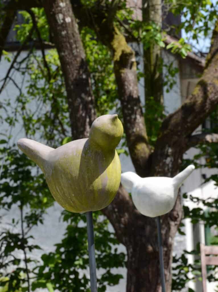 Skulpturen von Vögeln im Garten mit Bäumen im Hintergrund
